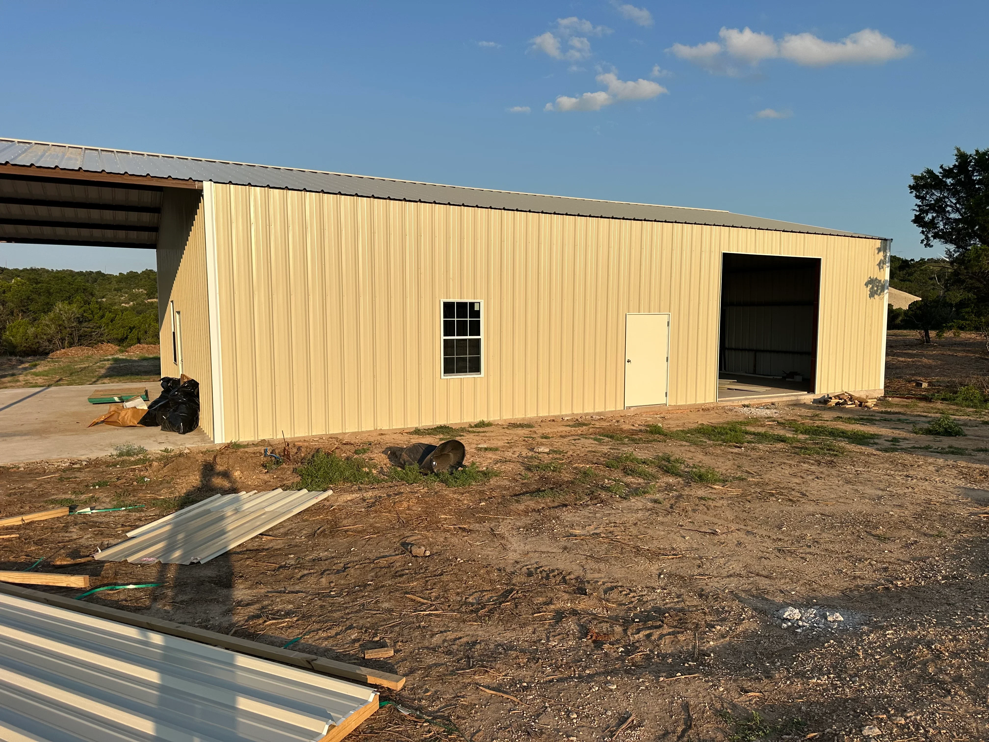 Cream-colored metal building with corrugated steel siding, metal roof, and large bay door