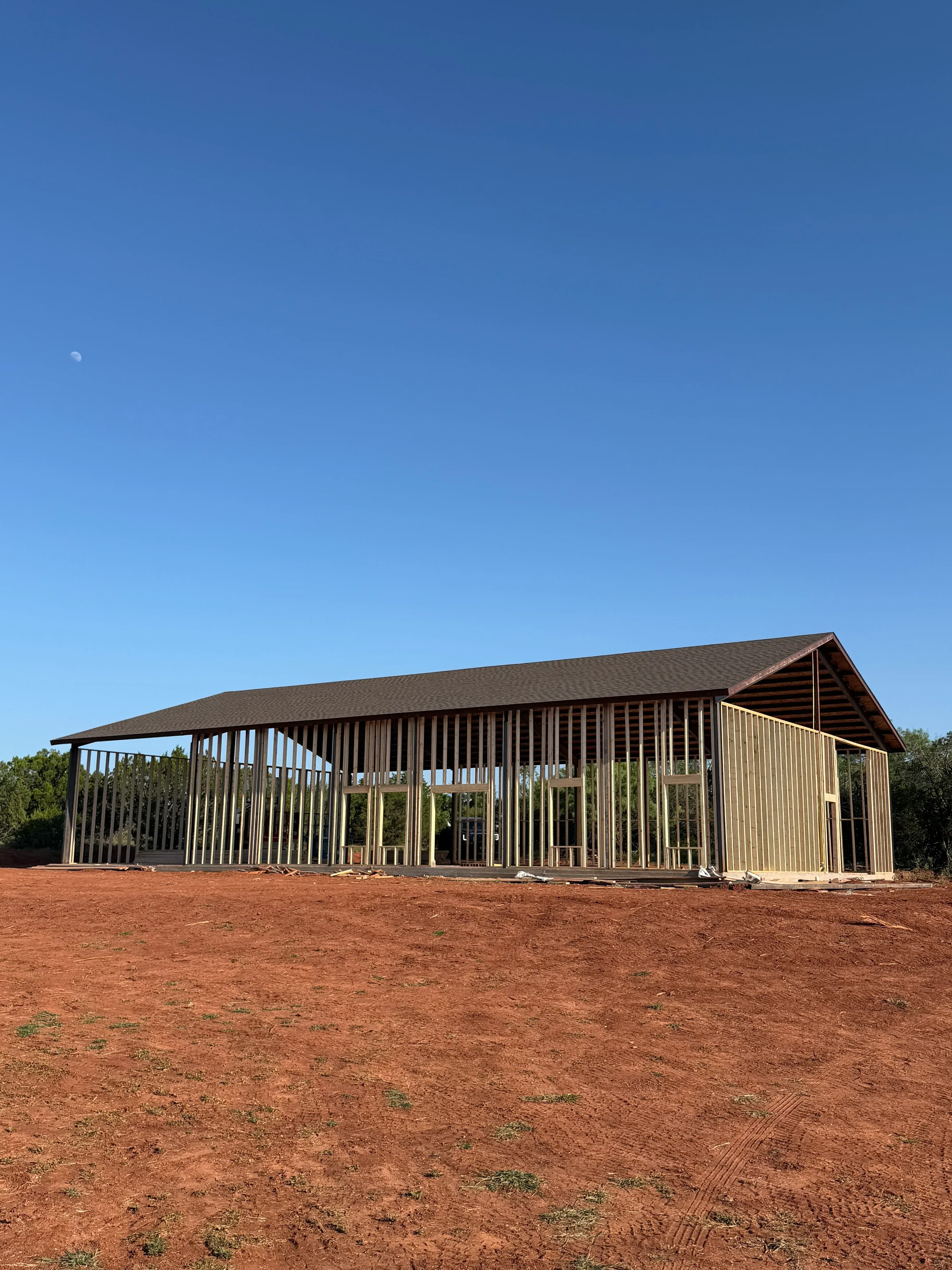 Metal louvered carport with horizontal slats and steel frame next to brick wall