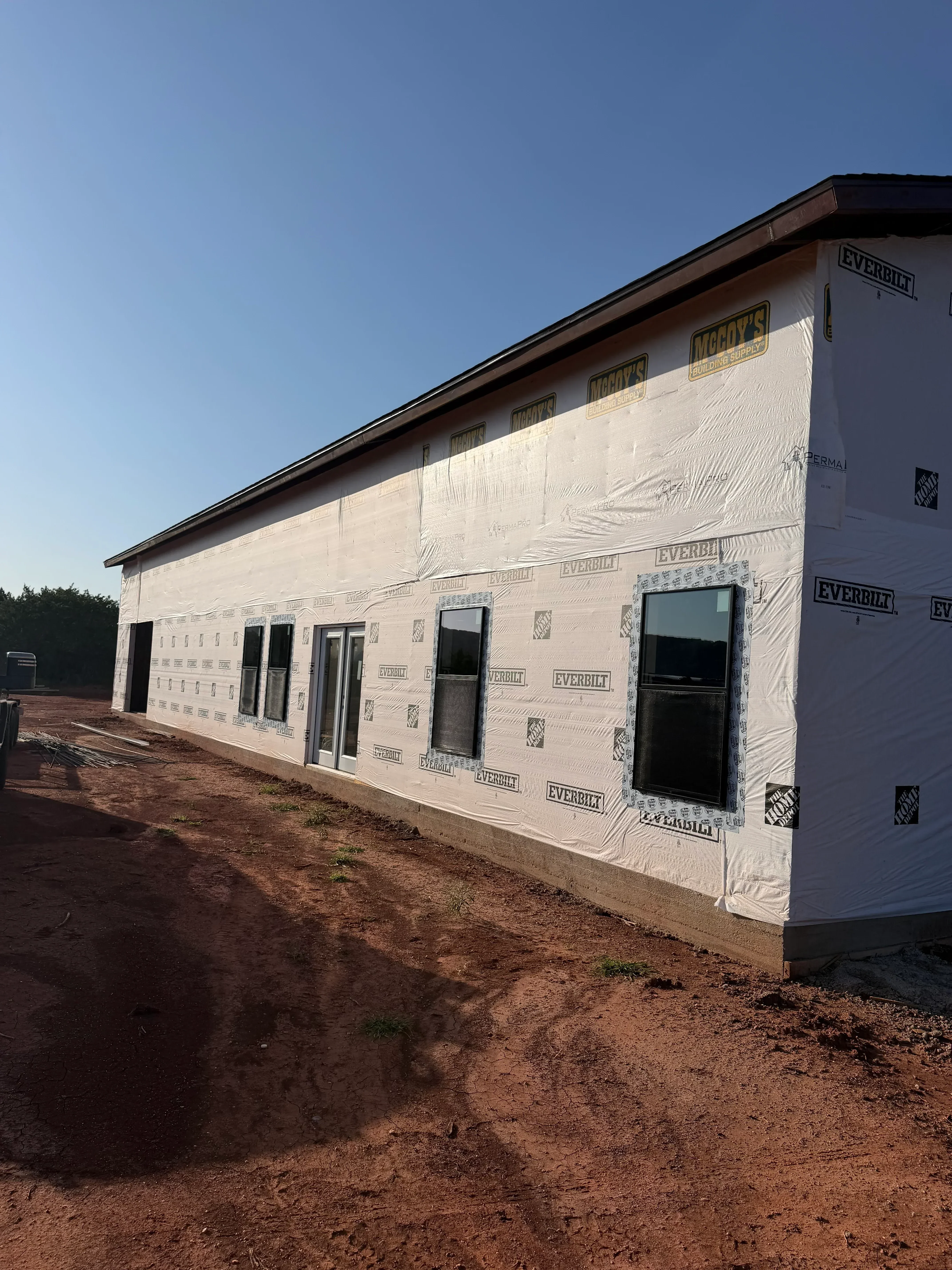 New home framing with house wrap, window openings, and roof underlayment installation