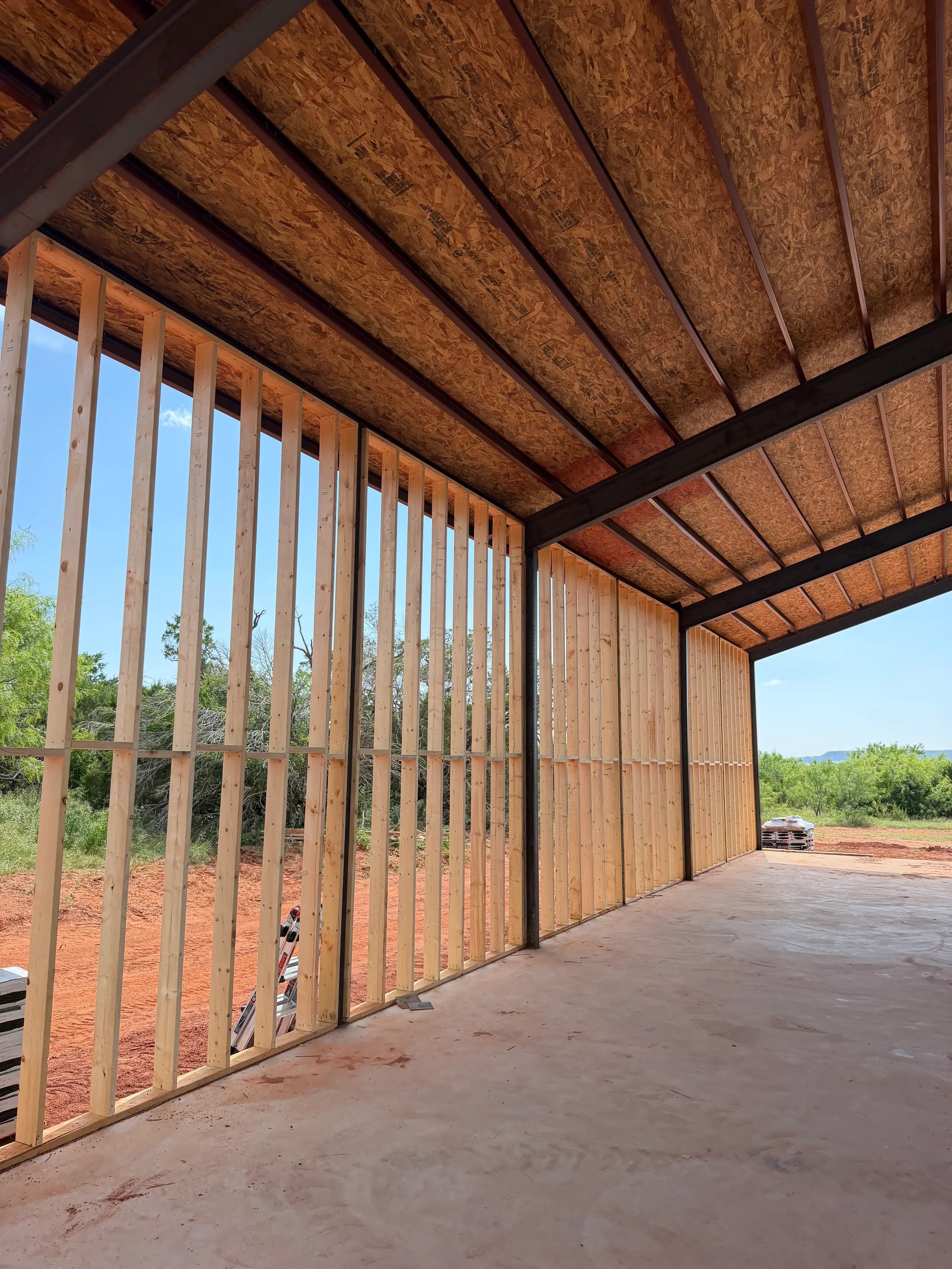 Roof framing with engineered trusses, OSB sheathing, and steel support beams during construction